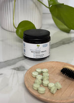 Load image into Gallery viewer, Jar of mouthwash tablets with tablets on a wooden plate on a marble surface.
